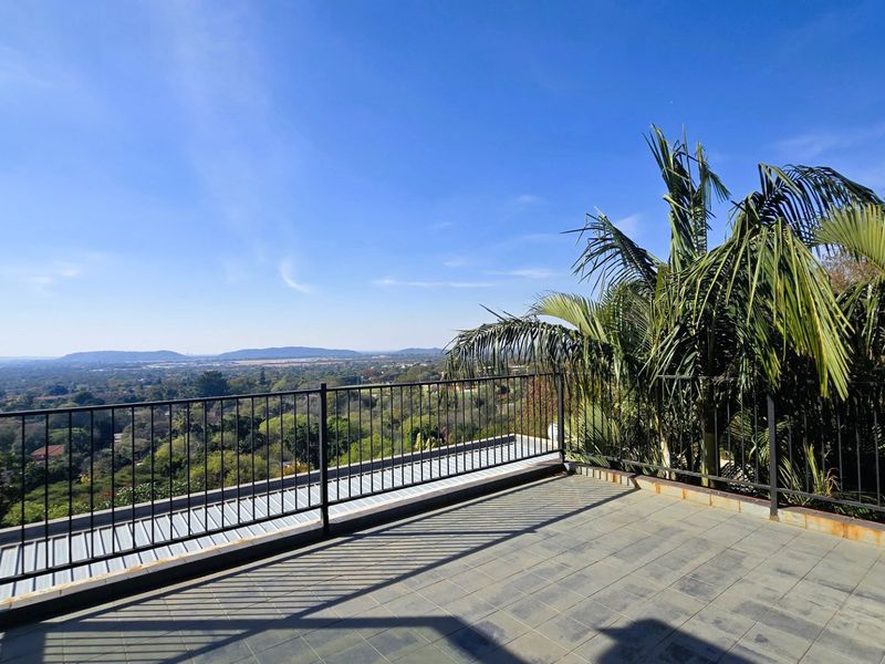 An elevated balcony featuring tiled flooring and a metal balustrade, offering expansive panoramic views of the surrounding landscape.