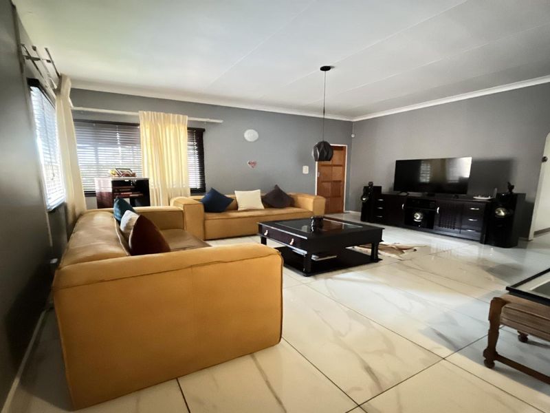 Spacious living room featuring large format marble-look floor tiles, neutral grey walls, and cove cornicing, providing a bright and contemporary foundation.