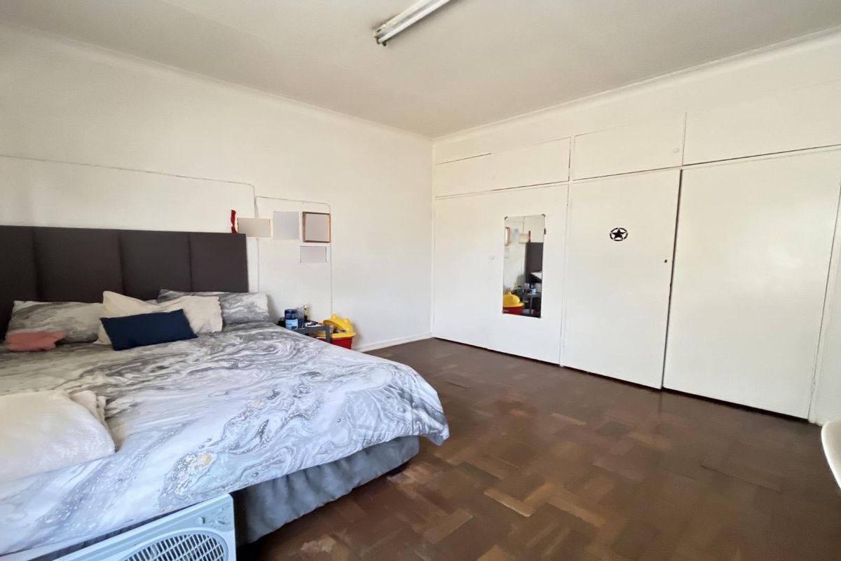 Spacious bedroom featuring classic parquet flooring and extensive built-in cupboard storage with overhead compartments.