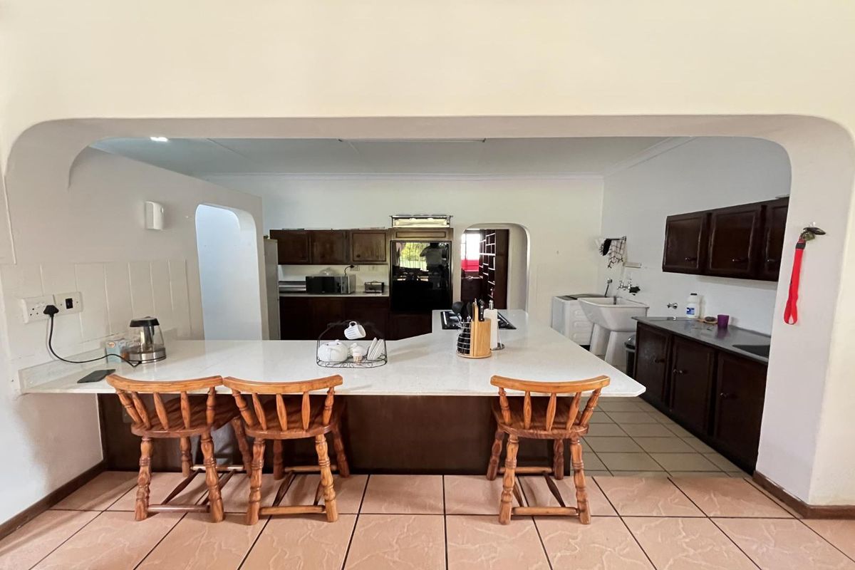 Spacious kitchen featuring a large central island with breakfast bar, dark wood cabinetry, and tiled flooring, offering a functional layout for cooking and dining.