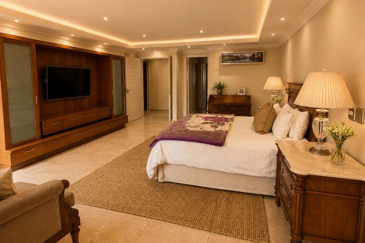 Spacious bedroom featuring polished tile flooring, recessed cove lighting, and extensive built-in cabinetry for storage.