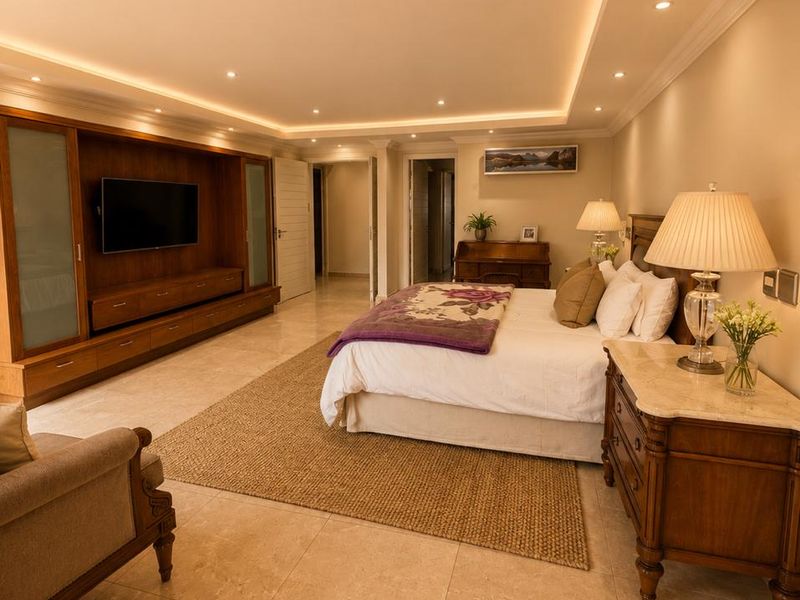 Spacious bedroom featuring polished tile flooring, recessed cove lighting, and extensive built-in cabinetry for storage.