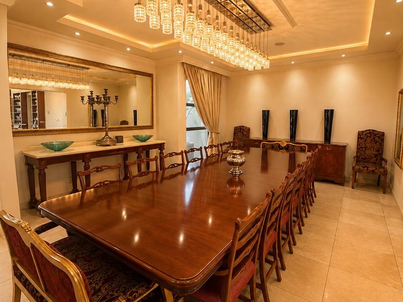 Elegant formal dining room featuring large-format tiled flooring, sophisticated recessed ceiling lighting, and a prominent crystal chandelier, creating a refined atmosphere for entertaining.