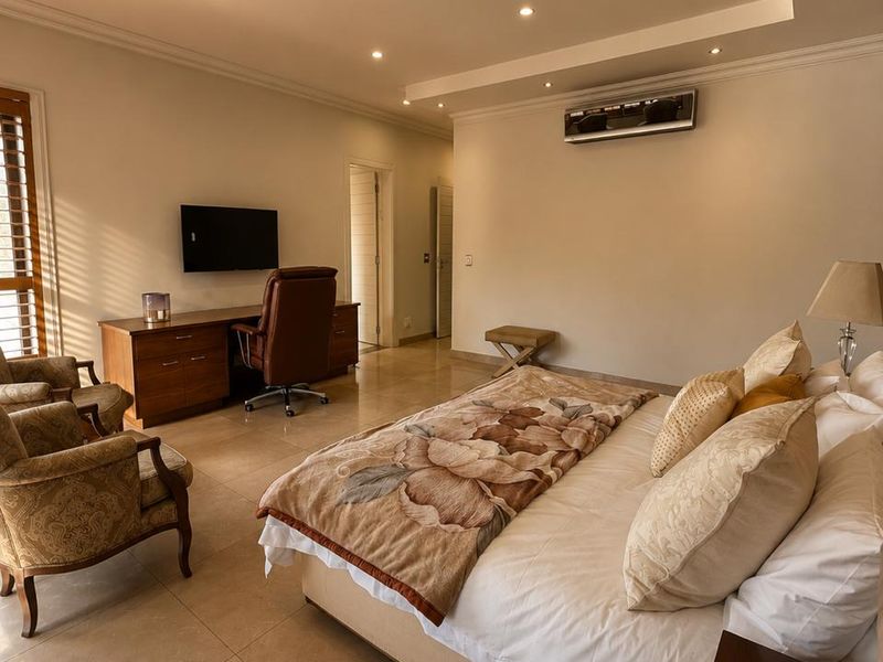 Spacious bedroom featuring tiled flooring, recessed ceiling lighting, a wall-mounted air conditioning unit, and plantation shutters.