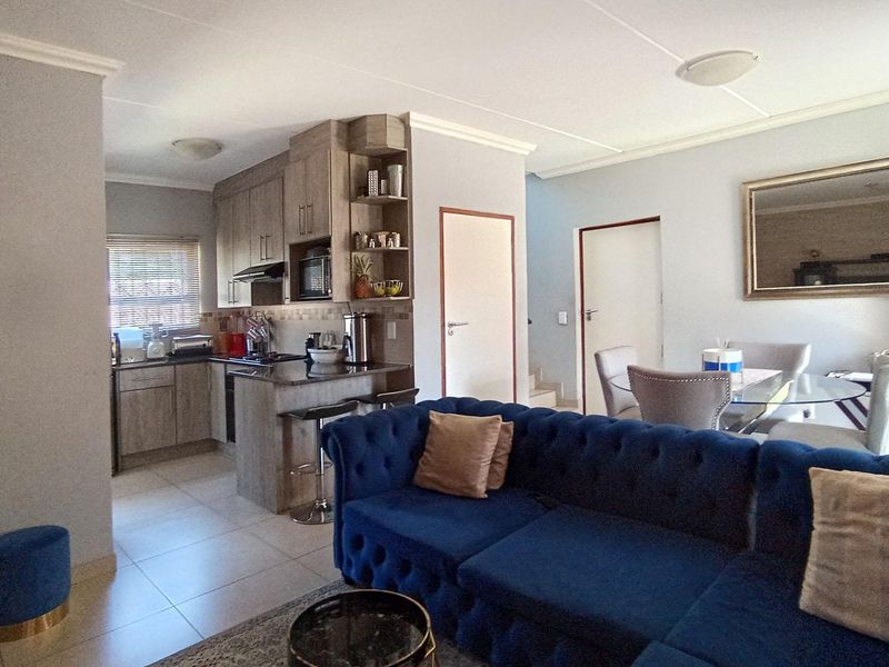 Open-plan living and kitchen area featuring modern cabinetry, granite countertops, and tiled flooring, creating a functional and cohesive living space.
