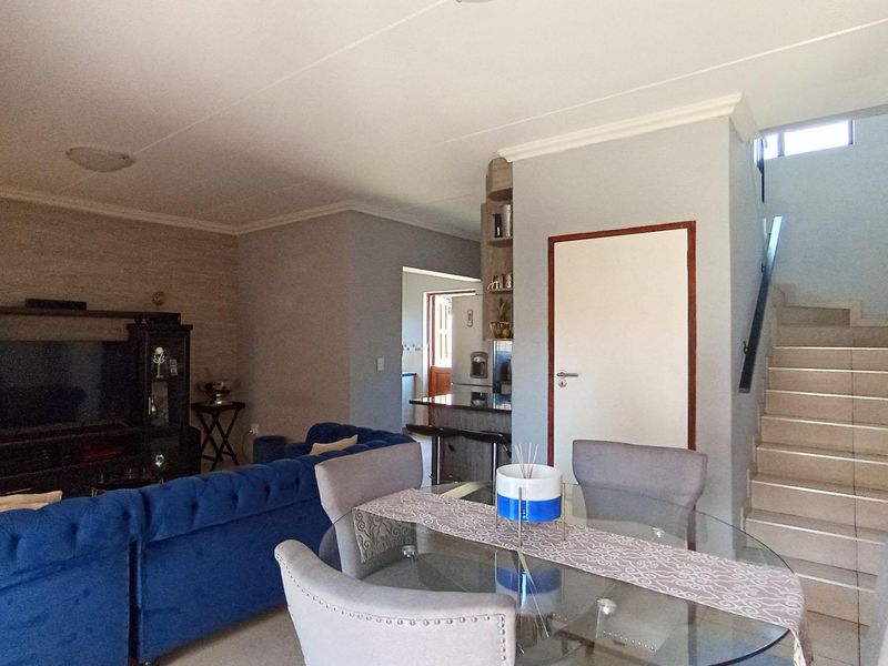 Open plan living and dining area featuring tiled flooring, a staircase, and neutral wall finishes, creating a functional and connected living space.