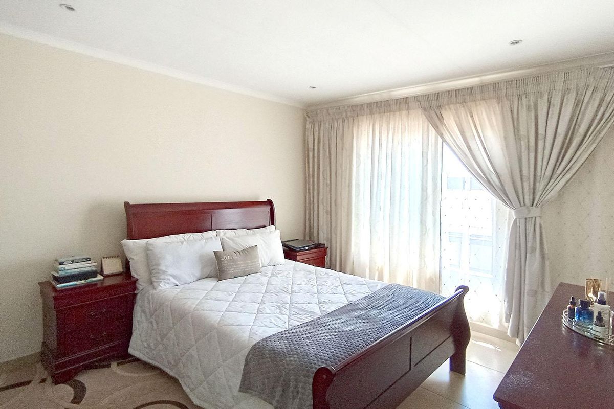 A well-maintained bedroom featuring tiled flooring, recessed downlighting, and a sliding glass door providing access to the exterior.