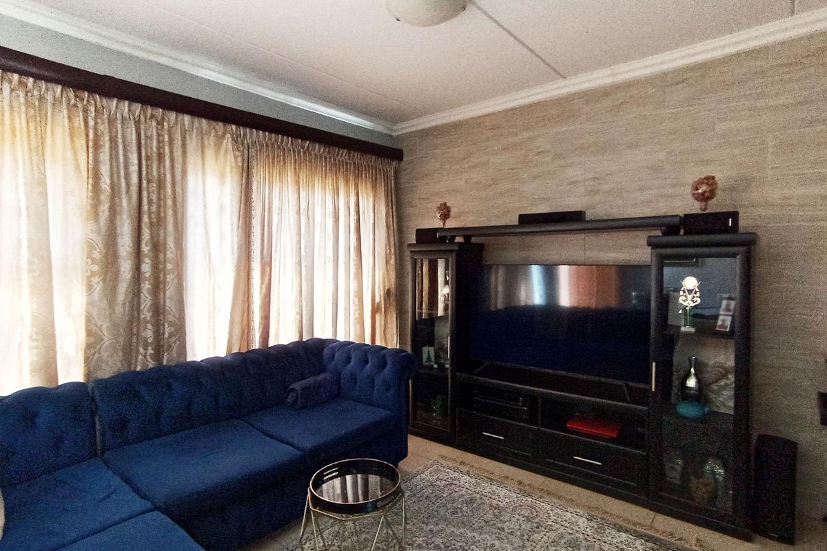 A living room featuring a textured accent wall, ceiling cornice detailing, and a flush mount light fixture.