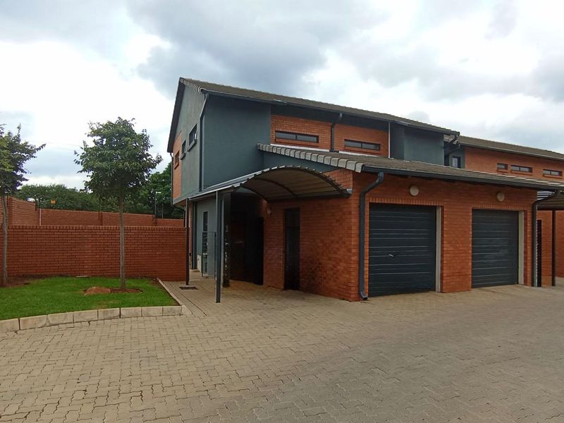 Front elevation of a modern townhouse featuring a double garage, brick facade, and a paved driveway with a covered entrance.