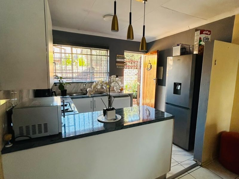 A functional kitchen featuring granite countertops, white cabinetry, tiled flooring, and direct access to an outdoor area.
