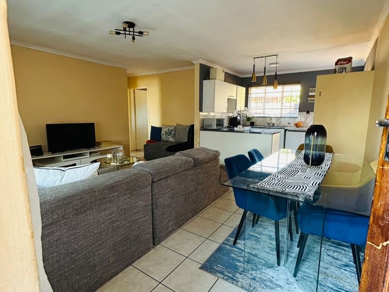 Open-plan living and dining area featuring tiled flooring and a functional kitchen space with built-in cabinetry.
