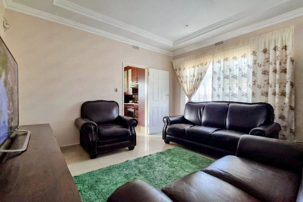 A comfortable living room featuring tiled flooring, crown molding, and direct access to the kitchen area.
