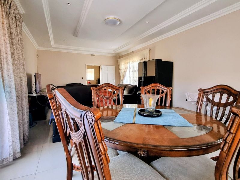Open plan living and dining area featuring tiled flooring, recessed ceiling details, and decorative crown molding throughout the space.