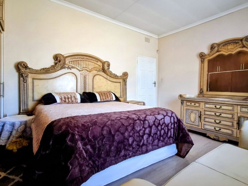 A spacious bedroom featuring laminate flooring, coved ceilings, and a built-in wardrobe, offering a functional layout with neutral wall finishes.