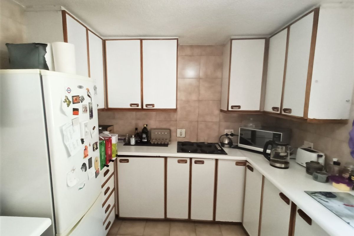 A functional kitchen featuring white cabinetry with wood trim, ceramic tile backsplash, and tiled flooring, offering a classic layout with integrated cooking appliances.