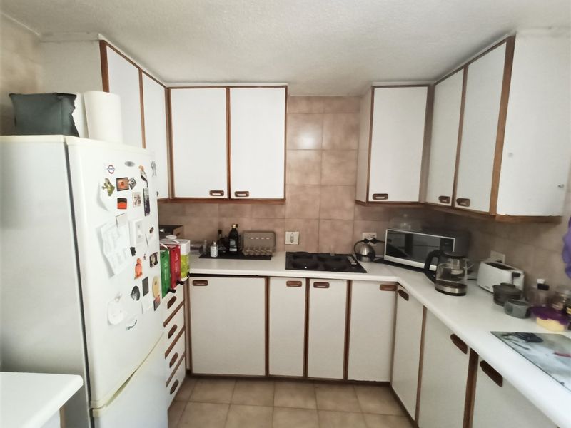 A functional kitchen featuring white cabinetry with wood trim, ceramic tile backsplash, and tiled flooring, offering a classic layout with integrated cooking appliances.