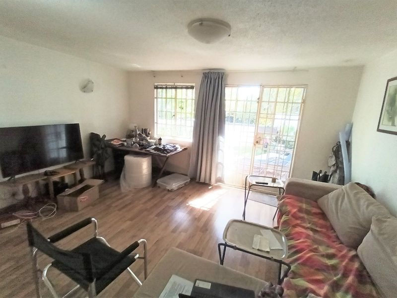 A living room featuring laminate flooring, security bars on windows, and a sliding door leading to the exterior.