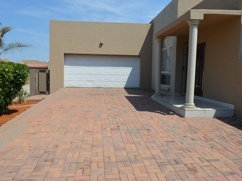 Front exterior view of the townhouse featuring a paved driveway, single garage, and a covered entrance porch with decorative columns.