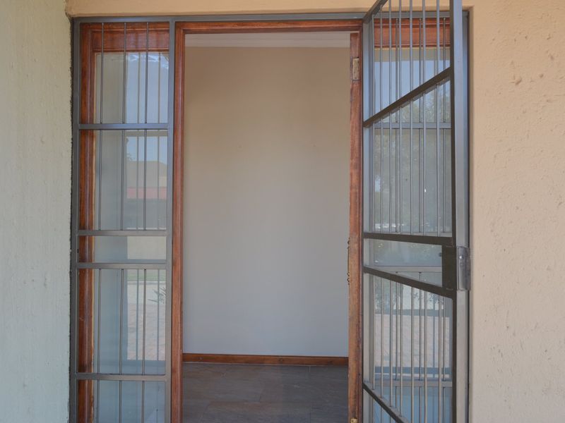 Entrance view featuring a security gate and wooden door frame leading into an empty, tiled interior space.