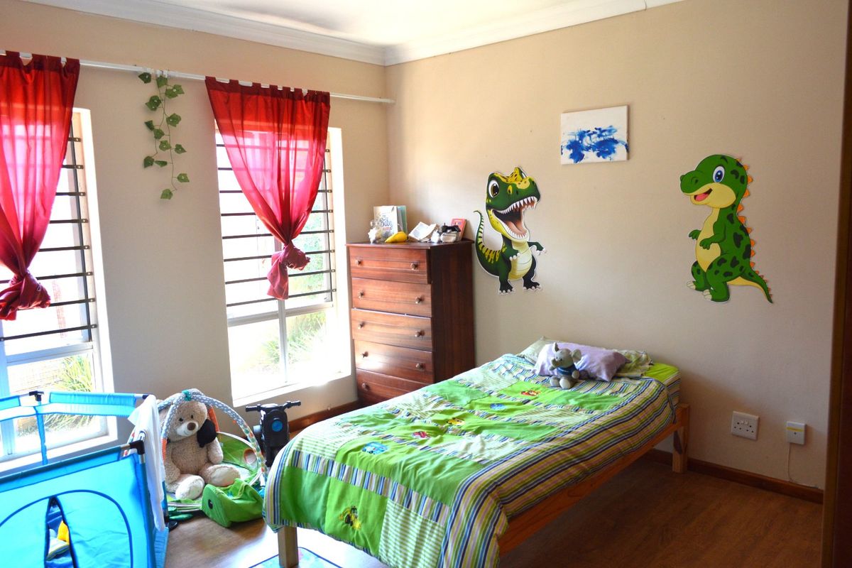 A bedroom featuring laminate flooring, large windows with security bars, and cove cornicing, providing a functional space with natural light.