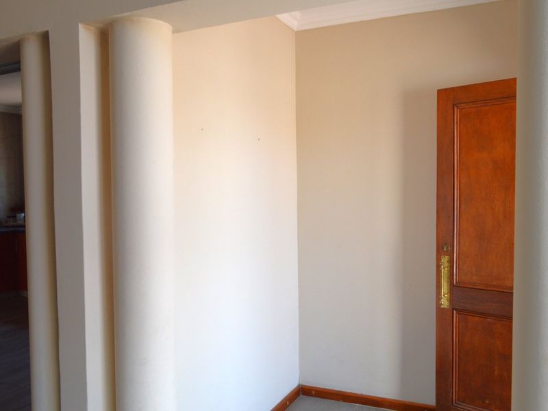 An empty entry area featuring architectural columns, a solid wooden door with brass hardware, and neutral wall finishes.