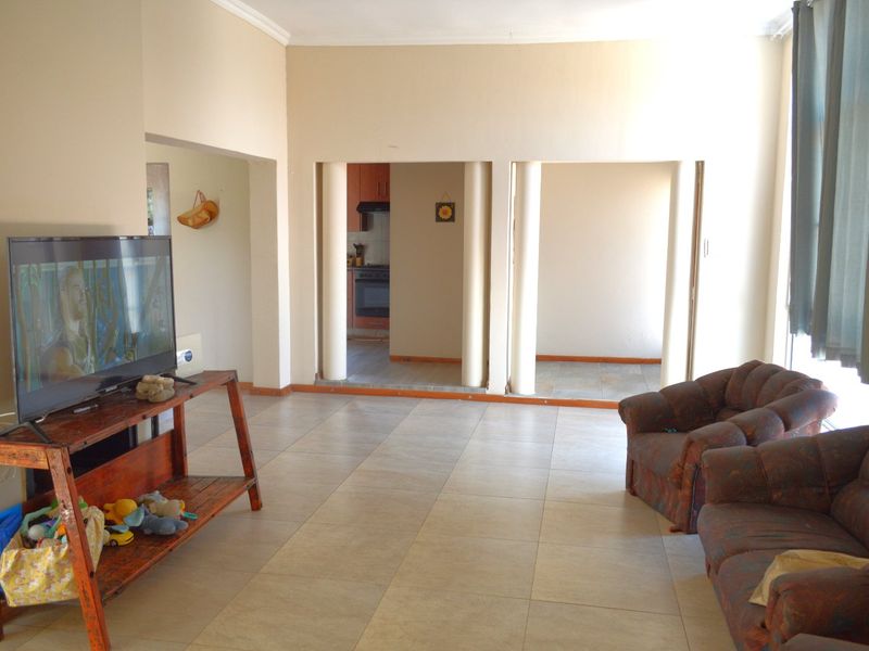 Open plan living area featuring tiled flooring and structural columns, with a view through to the kitchen area.