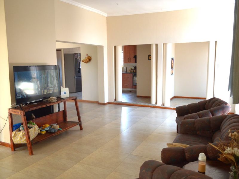 Spacious open-plan living area featuring tiled flooring, coved ceilings, and a view through to the kitchen with built-in cabinetry.