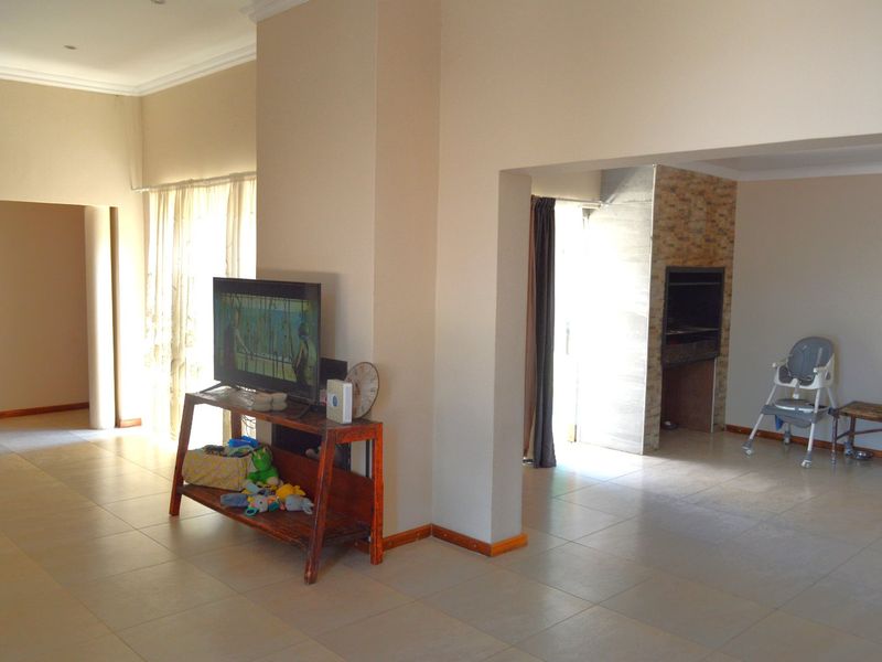 Open plan living area featuring tiled flooring, cornicing, and a built-in braai, providing a versatile space for relaxation and indoor entertaining.