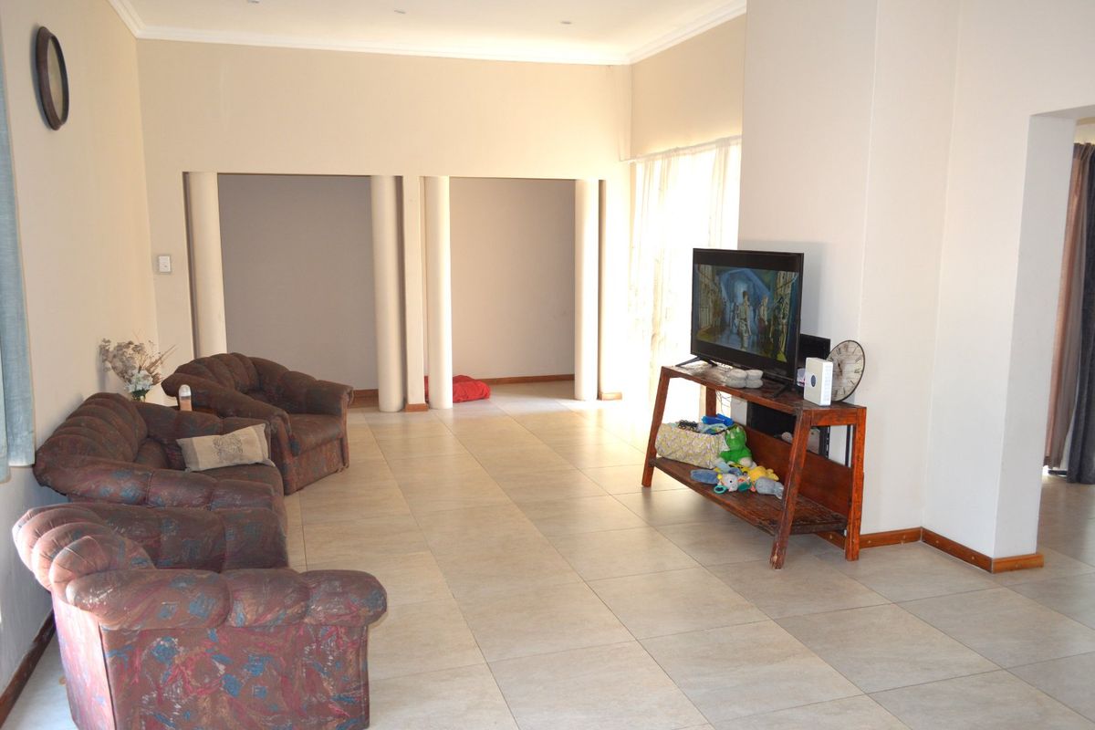 Spacious living area featuring large format floor tiles, structural columns, and neutral wall finishes, offering a versatile layout for comfortable family living.