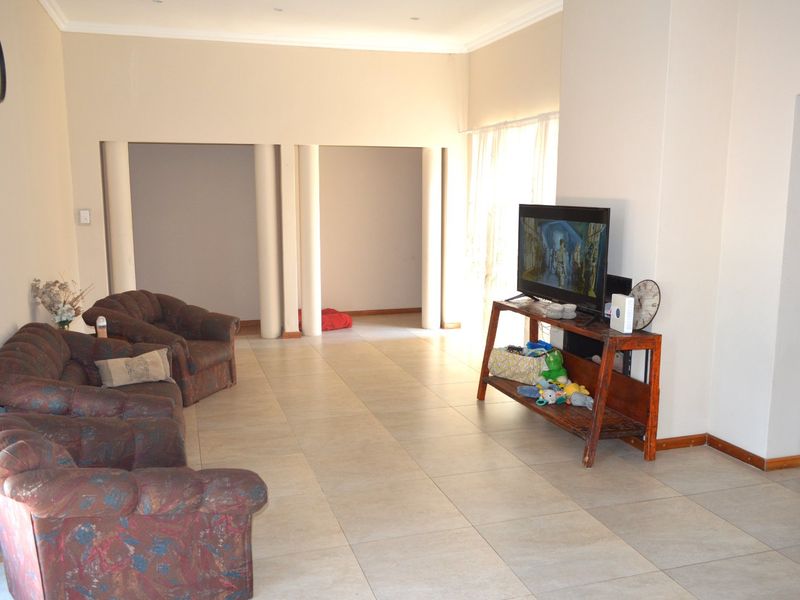 Spacious living area featuring large format floor tiles, structural columns, and neutral wall finishes, offering a versatile layout for comfortable family living.