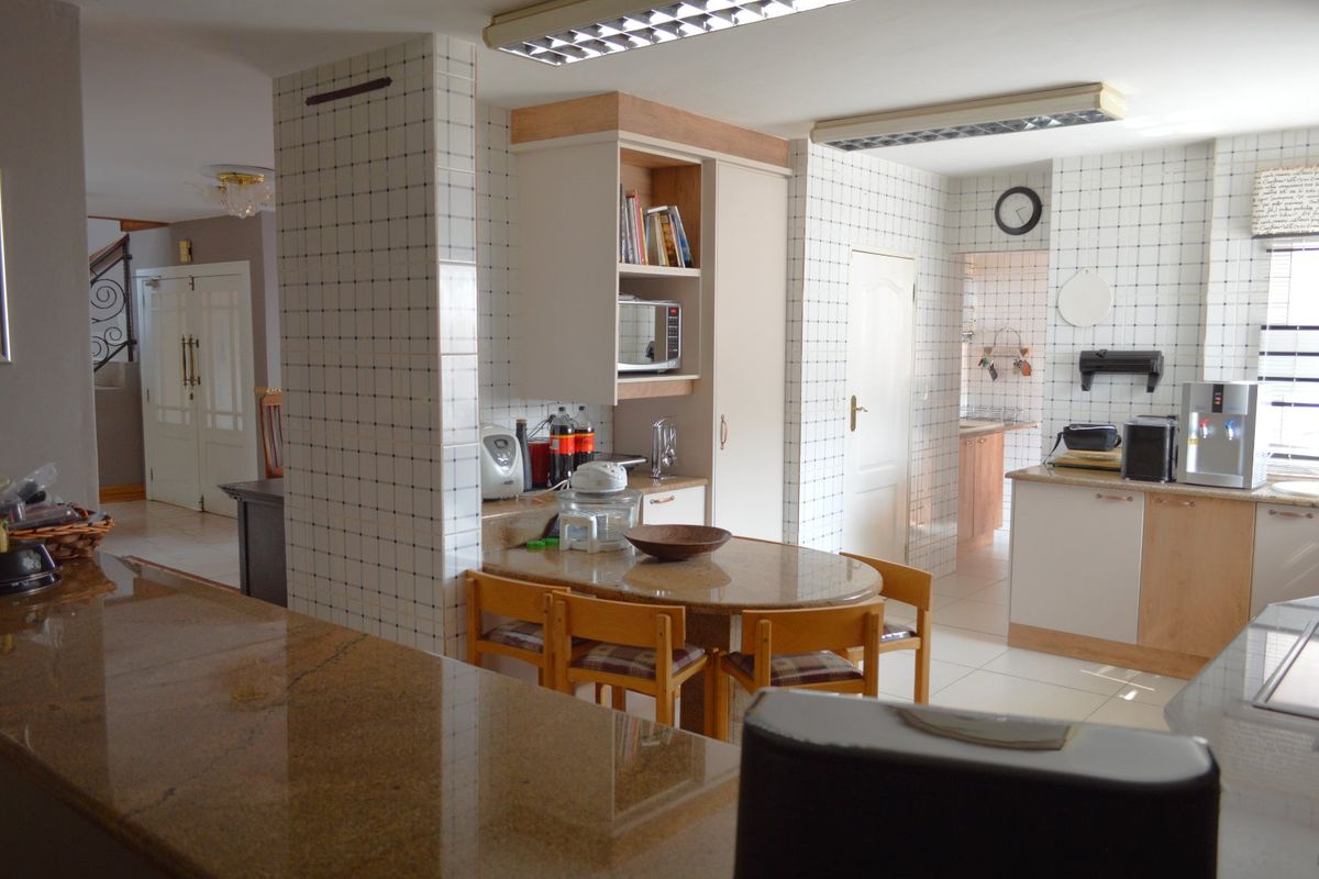 Spacious kitchen featuring granite countertops, extensive tiled wall finishes, and built-in cabinetry, offering a functional layout with an integrated breakfast nook area.