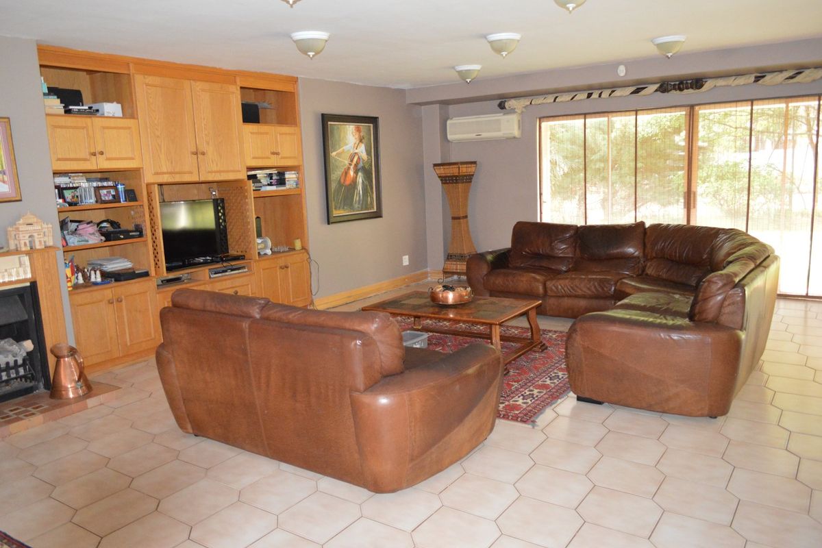 Spacious living room featuring built-in wooden cabinetry, a fireplace, split-system air conditioning, and large sliding glass doors leading to the exterior.