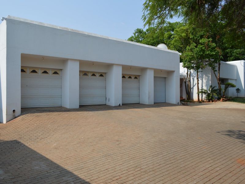 A spacious exterior view featuring a triple garage with white sectional doors and a large paved driveway area.