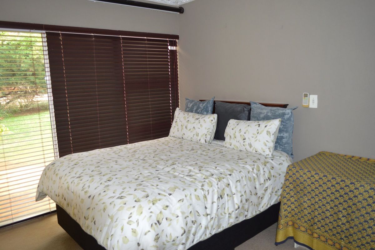 A bedroom featuring neutral wall tones, a sliding glass door with venetian blinds, and integrated air conditioning controls.