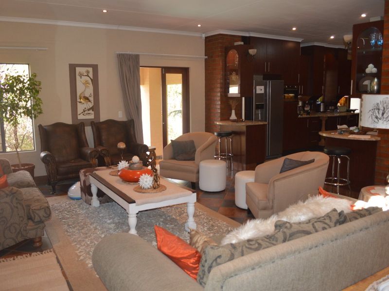 Spacious open-plan living area featuring an exposed brick wall, integrated kitchen with breakfast bar, and direct access to the outdoor patio.