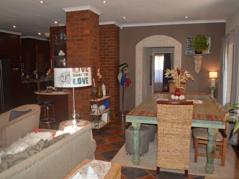 Open-plan living and dining area featuring an exposed brick pillar, tiled flooring, and recessed lighting, seamlessly connecting to the kitchen space.