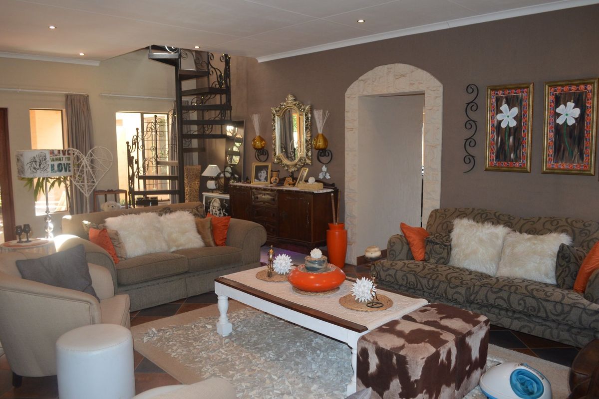 Spacious living room featuring a decorative spiral staircase, stone-clad arched entryway, and recessed lighting, offering a unique architectural layout.