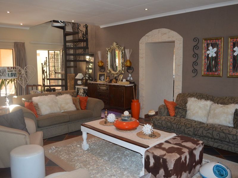 Spacious living room featuring a decorative spiral staircase, stone-clad arched entryway, and recessed lighting, offering a unique architectural layout.