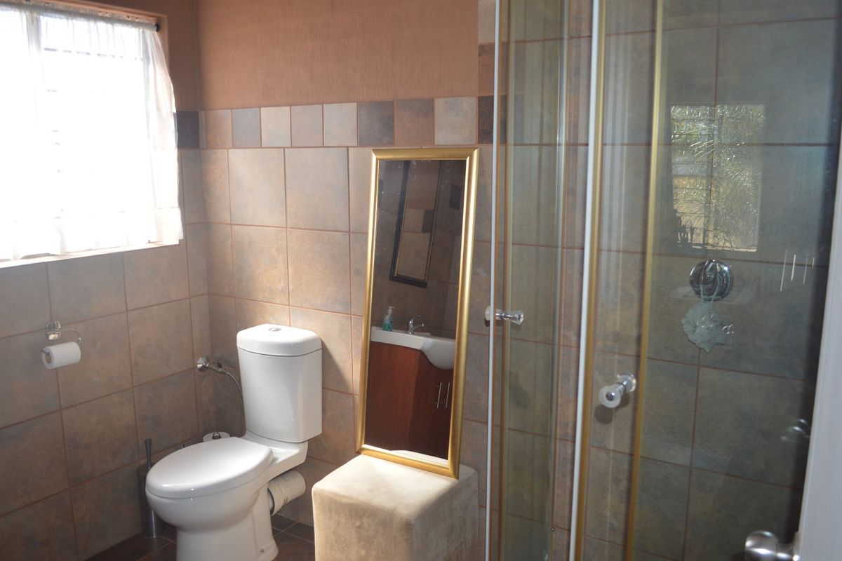 A functional bathroom featuring tiled walls, a standard toilet, and a glass-enclosed shower unit.