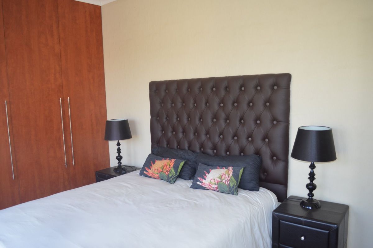 A bedroom featuring built-in wooden cupboards and neutral wall finishes.