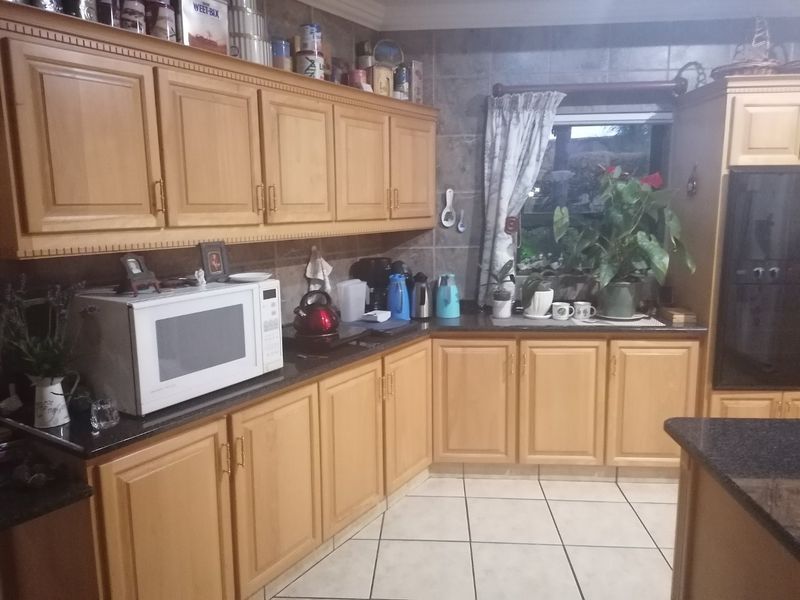 A functional kitchen featuring light wood cabinetry, dark granite countertops, tiled backsplash, and tiled flooring with a built-in oven.