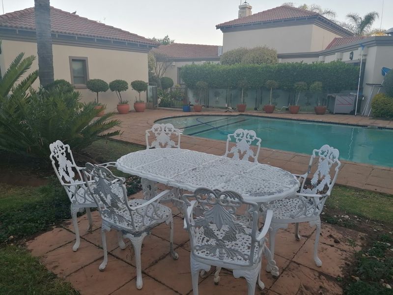 Outdoor pool area featuring a paved patio, swimming pool, and surrounding garden with perimeter walling.