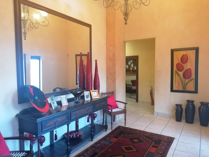Spacious entrance hall featuring neutral wall finishes, tiled flooring, and a decorative wrought iron chandelier.