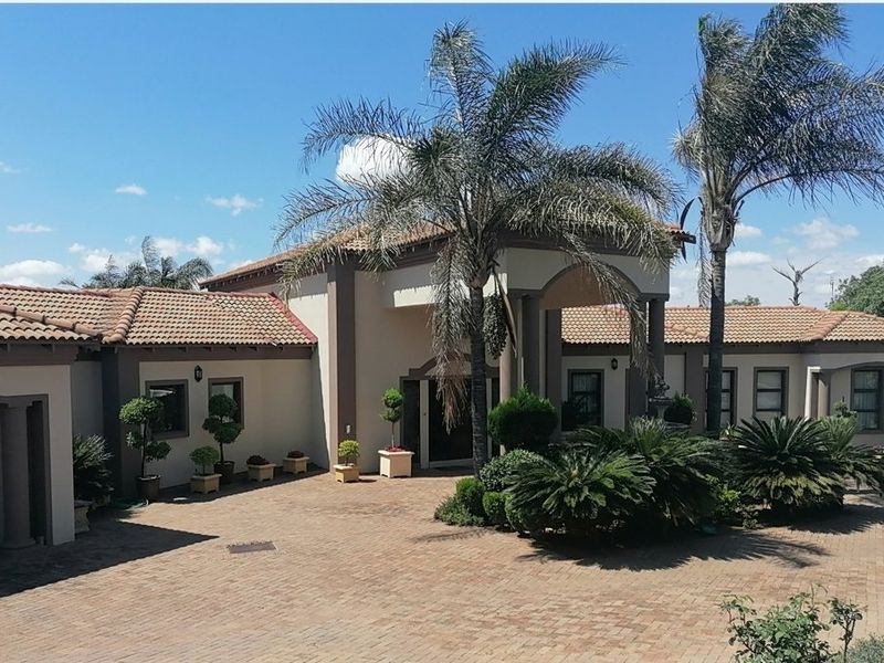 Front elevation of a well-maintained house featuring a paved driveway, covered entrance portico, and terracotta roof tiles.