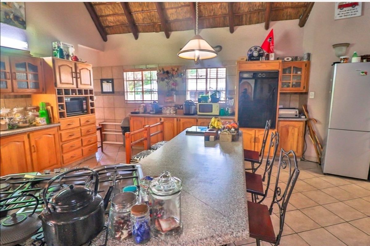 Spacious kitchen featuring wooden cabinetry, granite countertops, a central island, and a distinctive exposed thatch ceiling.