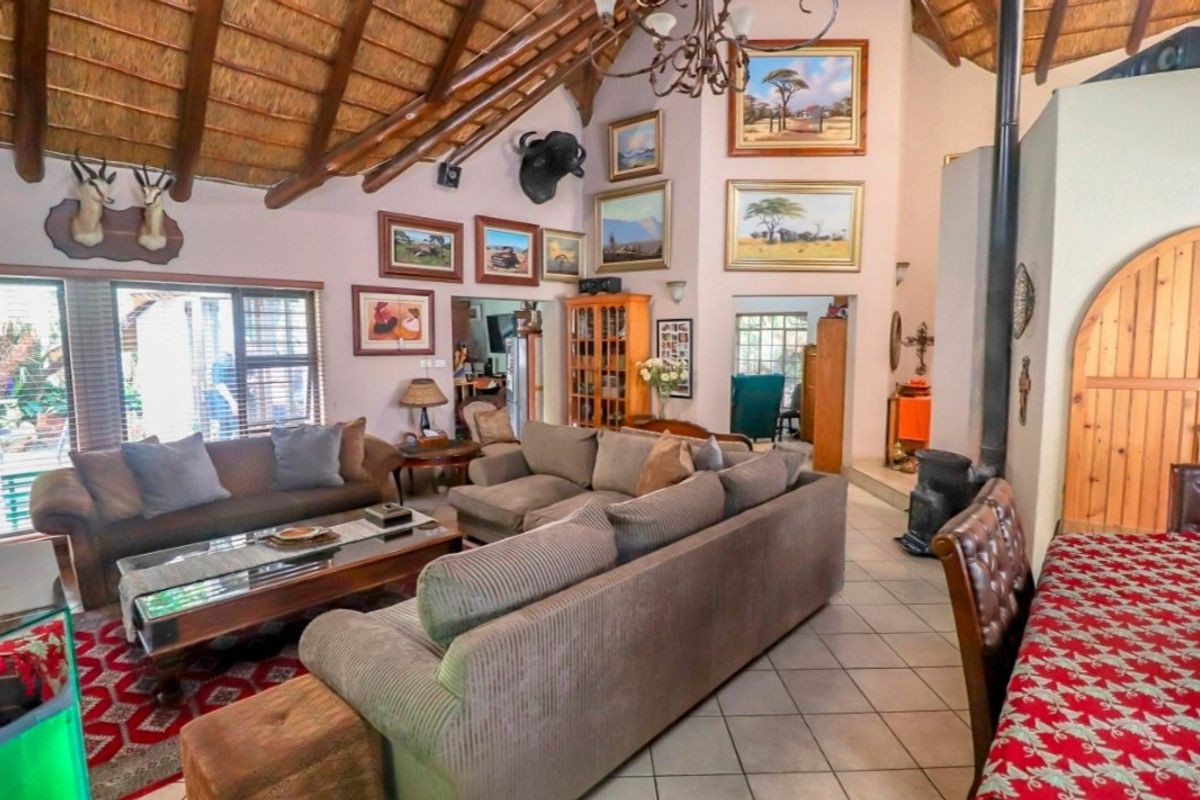 Spacious living room featuring a high vaulted thatched ceiling with exposed timber rafters, tiled flooring, and a freestanding fireplace.