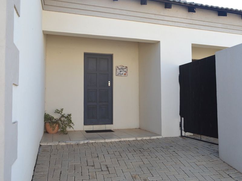 A neat townhouse entrance featuring a paved driveway, a covered porch area, and a solid panelled front door.