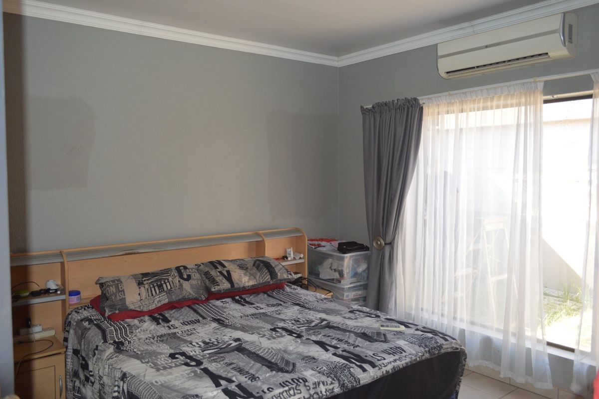 A bedroom featuring crown molding, a wall-mounted split-system air conditioner, and a sliding glass door providing natural light.