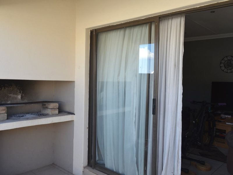 Covered patio area featuring a built-in braai and sliding glass door access to the interior living space.