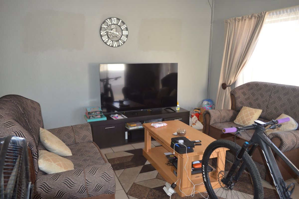 A functional living room featuring tiled flooring and neutral wall tones, providing a comfortable space for relaxation and entertainment.